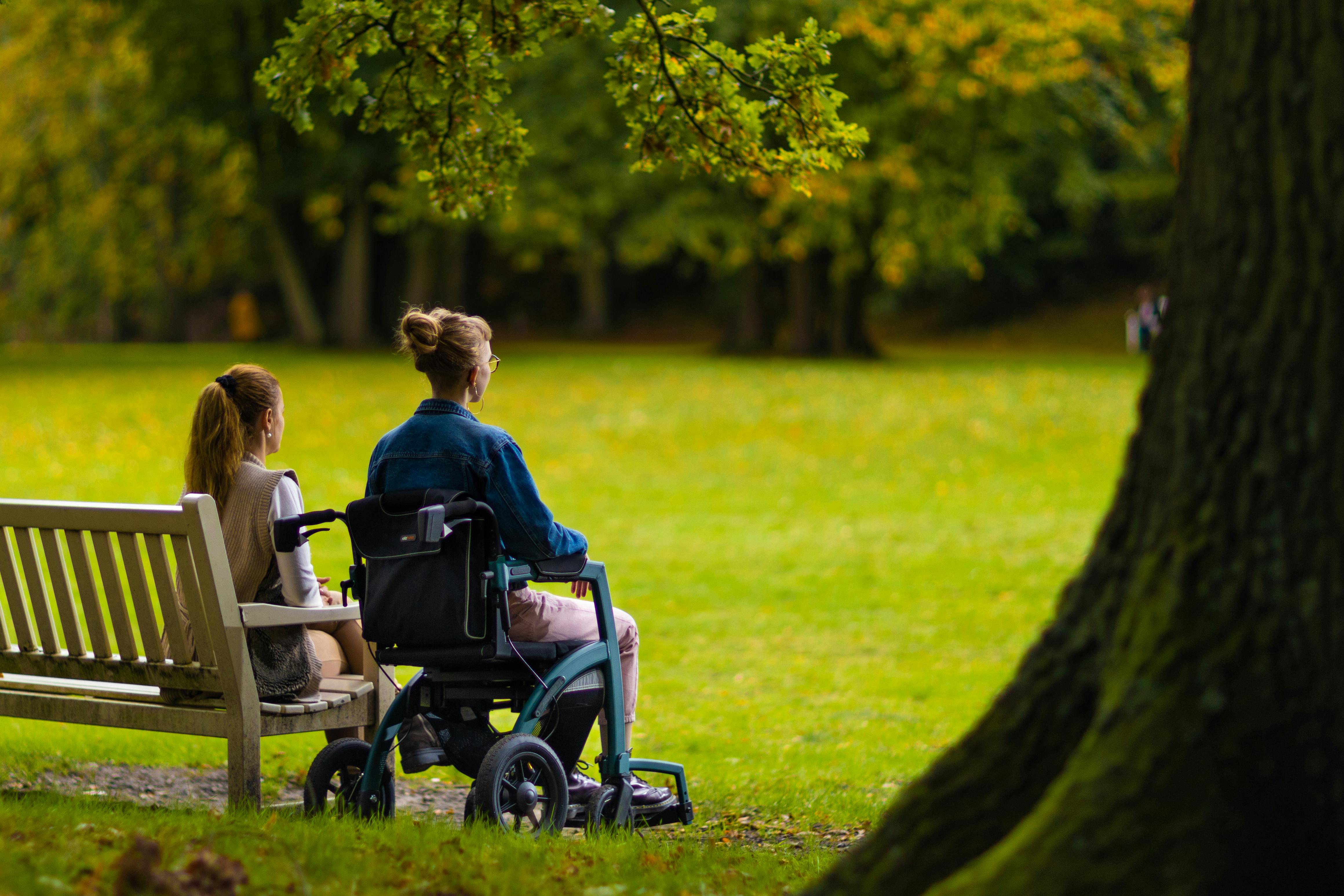 Two women, one in a wheelchair, enjoying a peaceful moment in the park